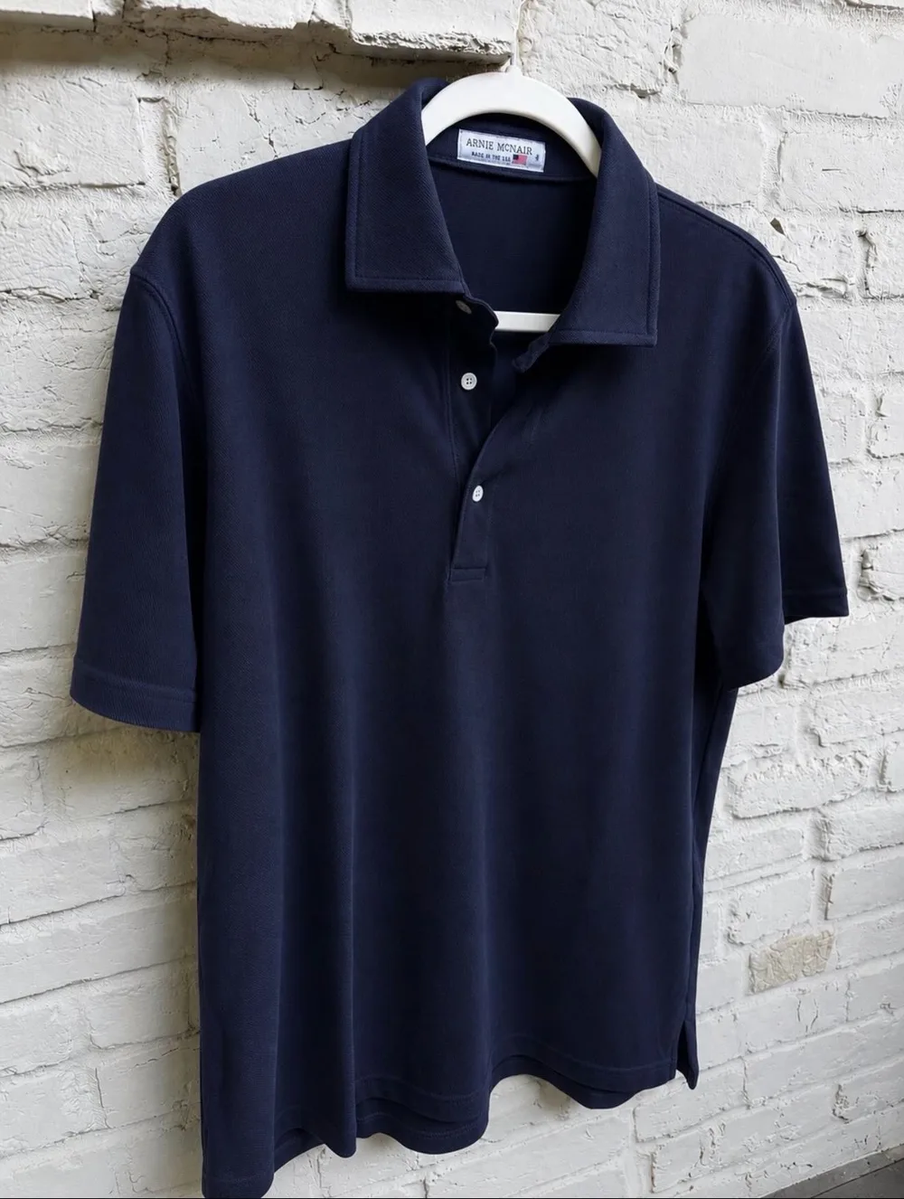 Navy Arnie McNair McNair Polo on a hanger, with a Made in the USA flag label