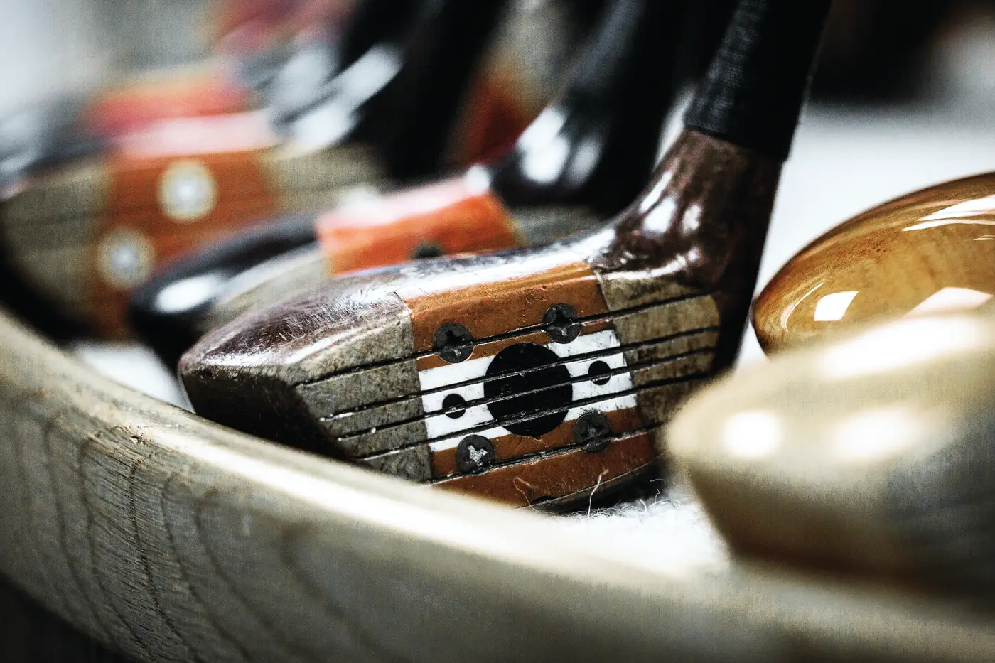 Vintage Honma persimmon woods with red and white face inserts in a wooden tray.