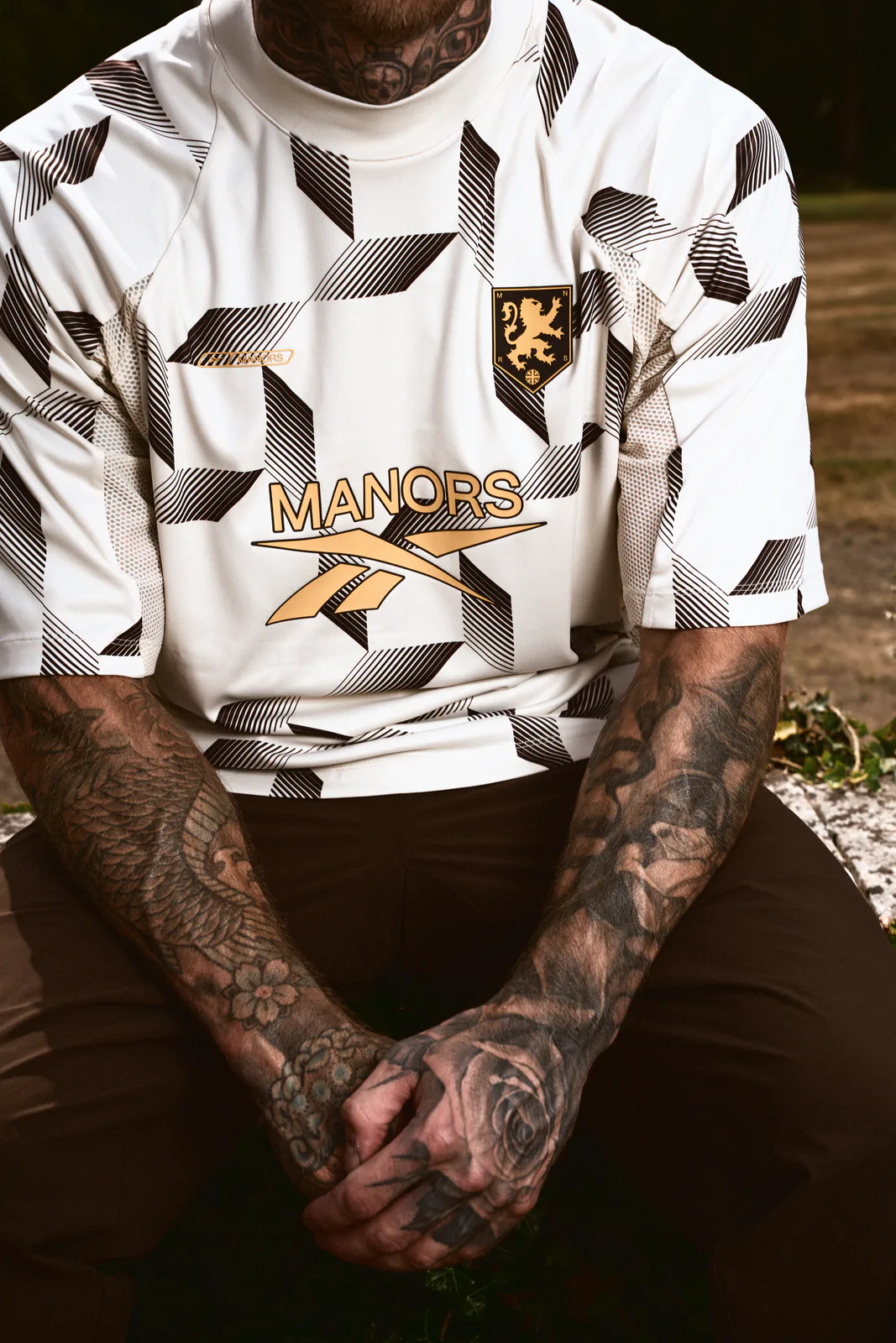 Detail view of the Reebok x MANORS mock neck polo showing the all-over print and collar construction.