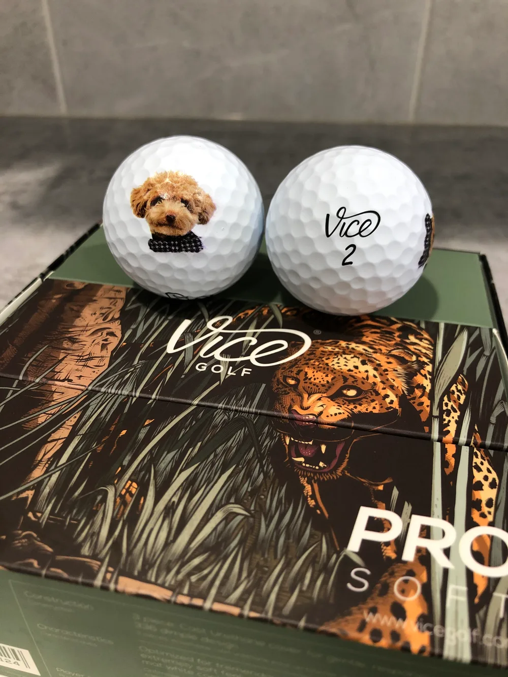 Custom Vice golf ball printed with a dog's face next to a standard Vice ball